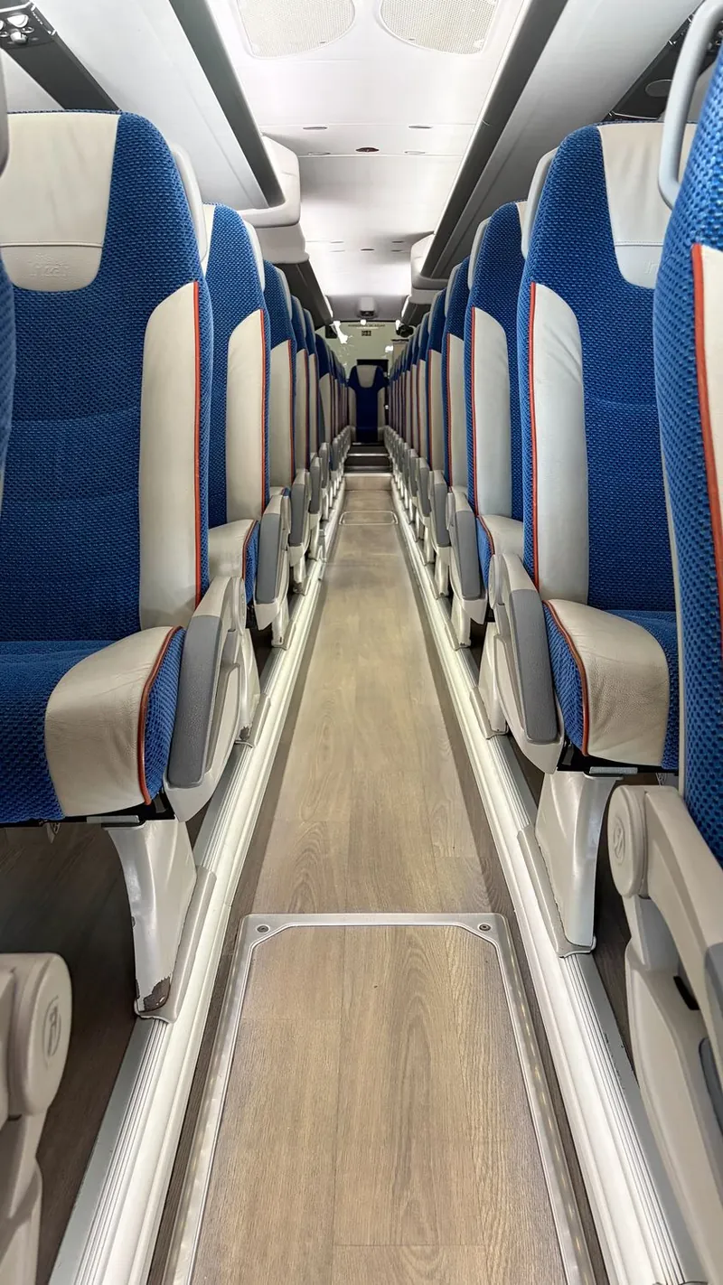 Interior de otro autobús con asientos azules y claros y pasillo central